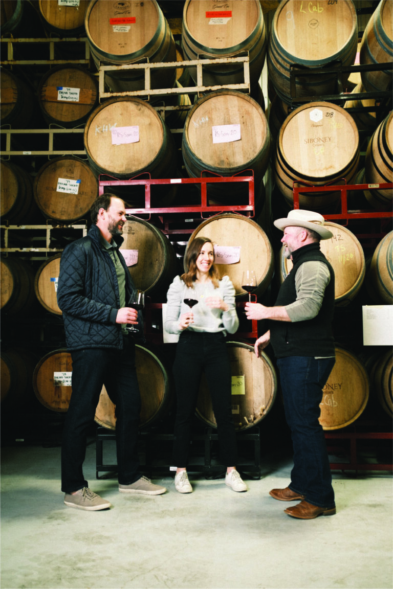 Wine tasting in front of barrel wall inside a winery in Fredericksburg, Texas with Noblemen Wines owners Austin and Katie Pitzer.